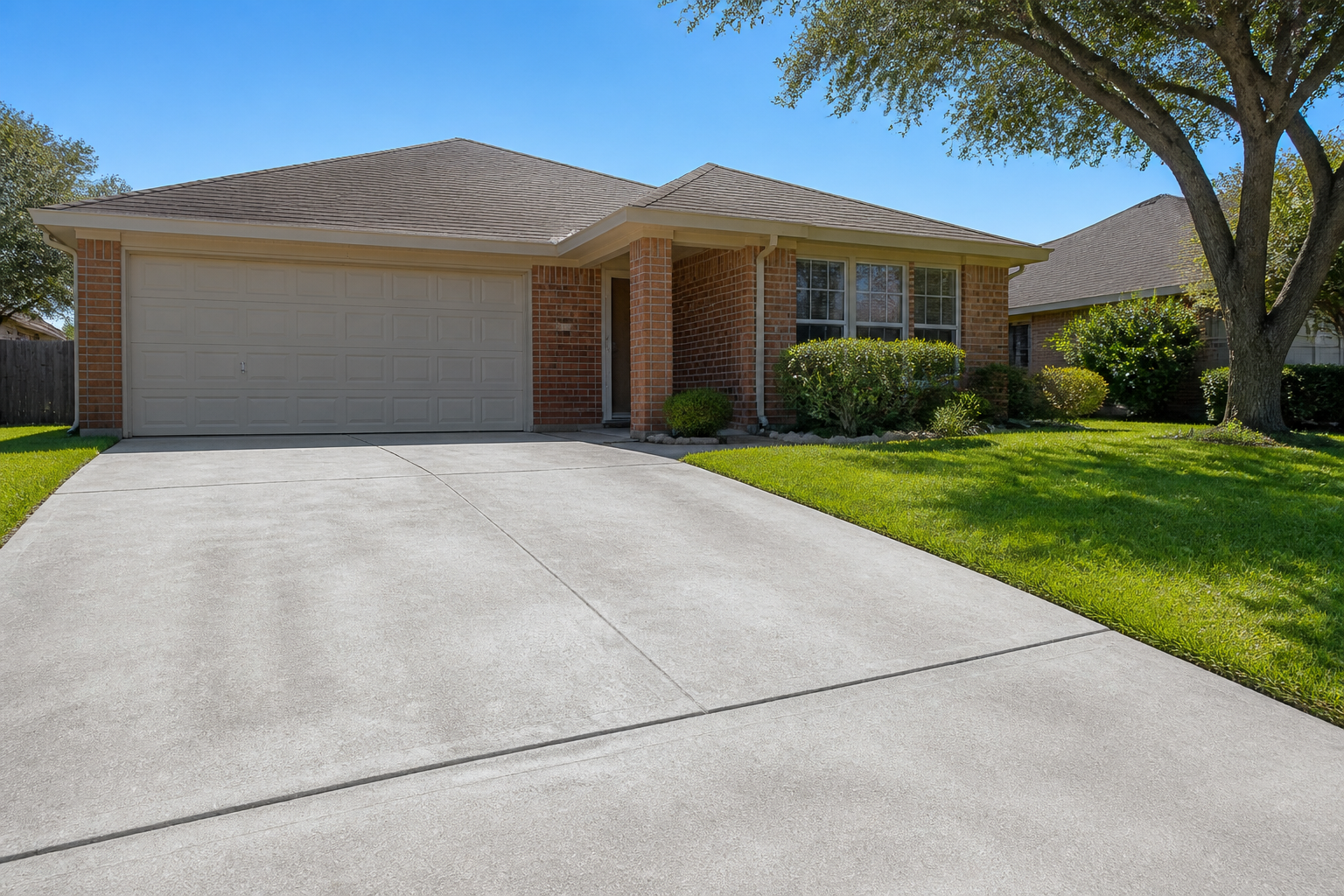 A clean concrete driveway in front of a San Antonio home after being professionally cleaned and sealed, preventing cracks and stains.