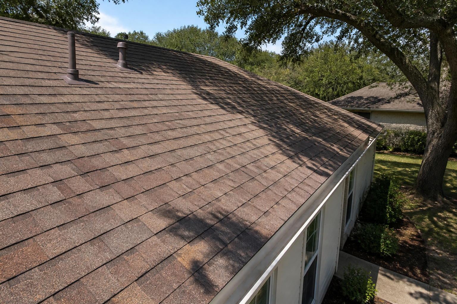 An asphalt shingle roof on a San Antonio home, showing signs of aging suitable for a roof rejuvenation treatment alternative.